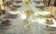 long wedding table with white table cloth and elegant tableware and roses in the middle