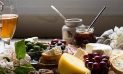cheese platter with grapes and relish and salami with a glass of beer