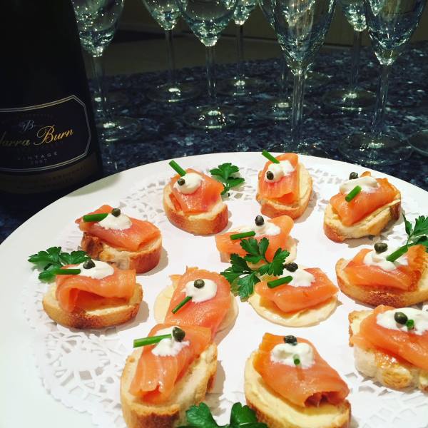 smoked salmon canapés on a platter with champagne and glasses